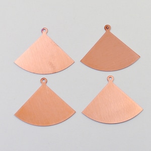 May include: Four copper-colored metal pendants in the shape of a triangle with a rounded bottom. Each pendant has a small hole at the top for hanging.