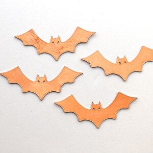 K&ouml;nnte beinhalten: Vier orangefarbene Papierflederm&auml;use mit einem einfachen Design. Die Flederm&auml;use sind ausgeschnitten und haben eine leicht strukturierte Oberfl&auml;che.