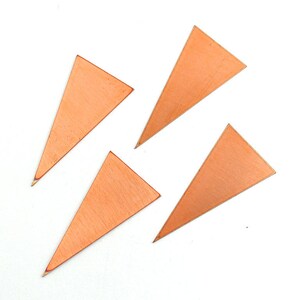 May include: Four copper triangle shapes, each with a smooth, slightly textured surface.