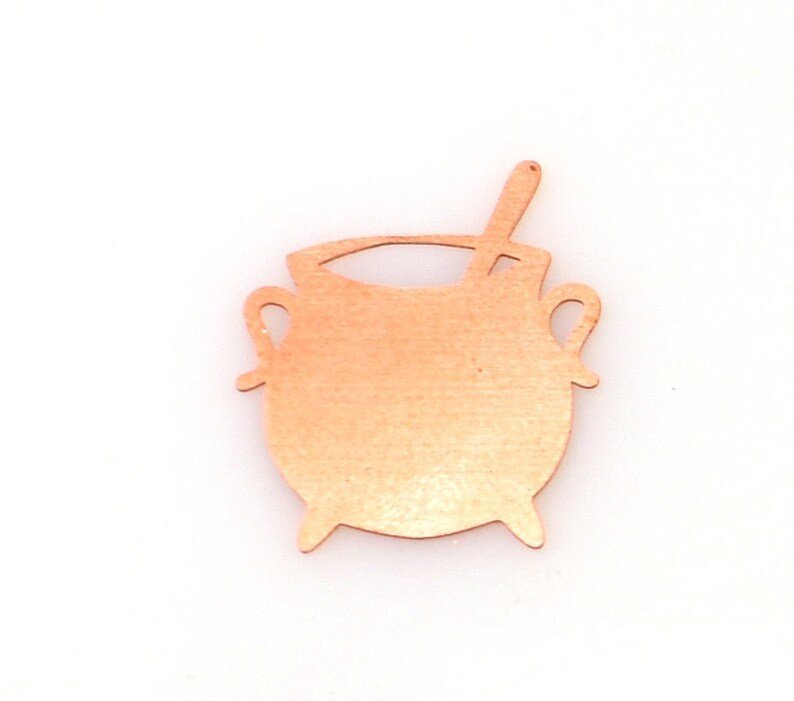 May include: A copper-colored metal cutout of a cauldron with a handle and a small spoon on top.