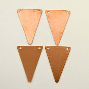 May include: Four copper triangle shapes with two holes each. The triangles are approximately 2 inches in length.