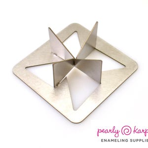 May include: A silver-colored metal enamel kiln stand with a square base and four triangular cutouts. Four vertical metal supports are positioned in the center. The logo "pearly karpel ENAMELING SUPPLIES" is in the bottom right corner.