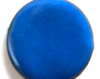 May include: A round, cobalt blue object with a dark brown edge. The surface has a slightly textured appearance. The object is set against a white background. The overall shape is a perfect circle.