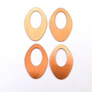 May include: Four oval-shaped wooden earrings with a hole in the center. The earrings are a light brown color.