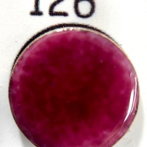 May include: A round, flat, purple button with a white swirl pattern. The button is labeled with the number 126.