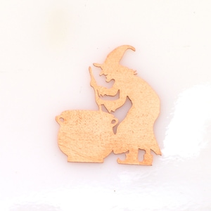 May include: Wooden cutout of a witch stirring a cauldron. The witch is wearing a pointed hat and has a long, flowing robe. The cauldron is round and has a handle on each side.