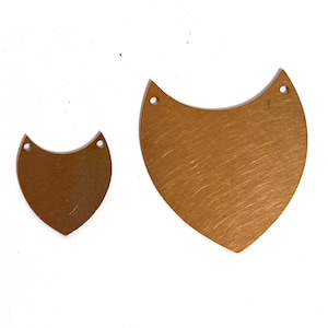 May include: Two gold-colored metal pendants in the shape of a crescent moon. The larger pendant is about 2 inches tall and the smaller pendant is about 1 inch tall. Both pendants have two holes at the top for attaching a chain or string.