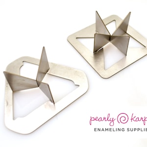 Puede incluir: Dos soportes de horno de esmalte de metal, uno cuadrado y otro en forma de diamante, con un diseño en forma de estrella en el centro. pearly@karpel enameling supplies.