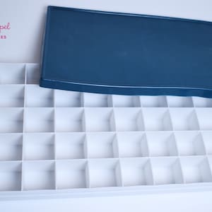 May include: A white plastic storage box with a blue lid. The box has 48 compartments and is empty.