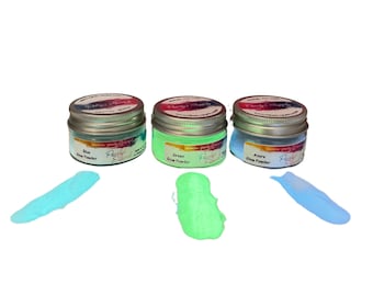 May include: Three small jars of glow powder in blue, green, and azure colors. Each jar has a silver lid and a label that says "Pearls & Supplies" and the color of the powder. The jars are sitting on a white surface.