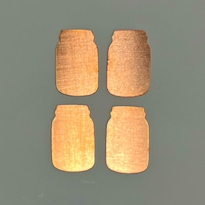 May include: Four copper-colored mason jar shaped metal cutouts. The cutouts are arranged in a two by two grid.