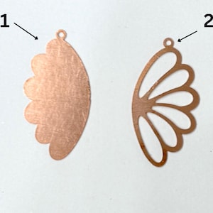 Op de afbeelding: Twee koperkleurige metalen oorbelcomponenten, elk in de vorm van een gestileerde vleugel of bloemblad. Eén is effen, de andere heeft een open, uitgesneden ontwerp. Beide hebben kleine lussen voor bevestiging, ideaal voor het maken van sieraden.