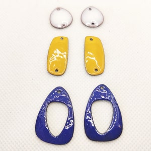 Puede incluir: Seis abalorios de esmalte en varias formas y colores. Dos son blancos, dos son amarillos y dos son azules. Los abalorios azules tienen un agujero en el centro.