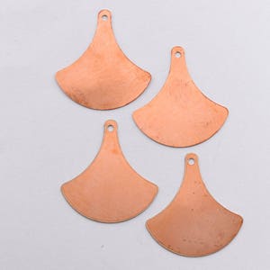 May include: Four copper-colored metal fan-shaped pendants with a hole at the top for hanging.