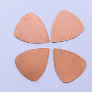 May include: Four copper guitar picks in the shape of a four-leaf clover.