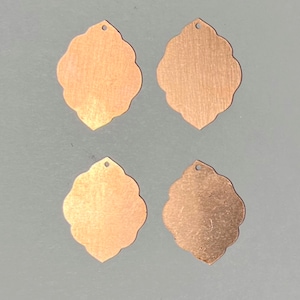 May include: Four copper-colored metal charms with a scalloped edge and a hole at the top.