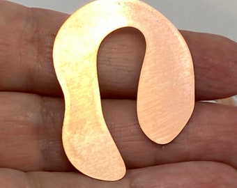 Puede incluir: Un colgante de metal de color cobre con forma de letra U estilizada con un acabado liso y cepillado.