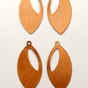 May include: Four copper-colored, leaf-shaped earring components. Each component has a teardrop shape with a large, open oval cut-out. A small hole is at the top for attachment. The metal has a brushed texture.