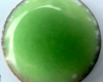 May include: A round, green ceramic tile with a white rim and a slightly textured surface.