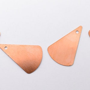 May include: Five copper-colored metal shapes with a hole in the bottom. The shapes are all triangles with rounded edges.