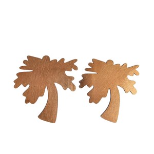 May include: A pair of gold-colored palm tree earrings. The earrings are made of metal and have a brushed finish.