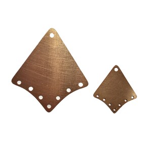 May include: Two copper-colored metal diamond-shaped pendants with multiple holes along the curved bottom edge and a single hole at the top. The pendants have a textured surface and are of different sizes.