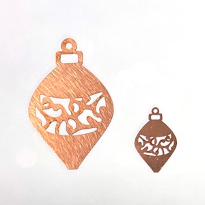 May include: Two copper-colored Christmas ornament cutouts with a decorative design. The larger ornament is about 4 inches tall and the smaller ornament is about 2 inches tall.