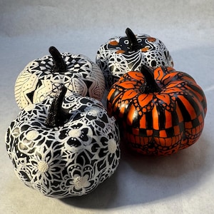 May include: Four decorative pumpkins painted in black and white with intricate patterns, and one pumpkin painted in orange and black stripes.