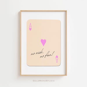 Könnte beinhalten: Ein druckbarer Kunstdruck mit einer Spielkarte mit einem As-Herz-Design. Die Karte ist rosa und pfirsichfarben mit dem Text "no risk, no fun!" in Schwarz.