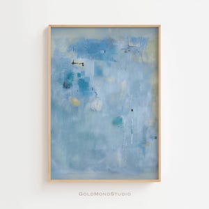 Könnte beinhalten: Abstrakter Kunstdruck in einem hellen Holzrahmen. Das Kunstwerk zeigt eine Mischung aus Blau-, Weiß- und Gelbtönen. Das Gemälde hat ein strukturiertes Aussehen mit Pinselstrichen und Farbschichten. Der Text "GOLDMONDSTUDIO" befindet sich in der unteren rechten Ecke.
