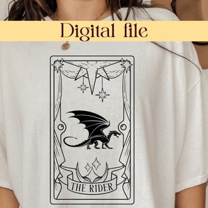 Puede incluir: Una camiseta blanca con una ilustración en blanco y negro de una carta de tarot. La carta representa un dragón negro con alas y el texto "THE RIDER".