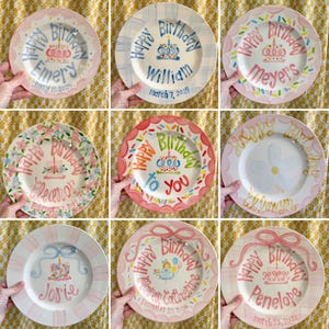 May include: Nine personalized plates with pink, blue, and white backgrounds. Each plate features a cake with a candle, a birthday message, and a name. The plates are decorated with flowers, sprinkles, and ribbons.