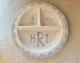 May include: A white ceramic divided plate with blue scalloped edges. The plate has three sections and the initials "HRT" are written in blue in the center section.
