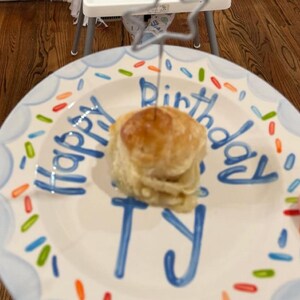 May include: A birthday cake on a decorative plate. The plate has a blue border and the words "Happy Birthday Ty" written in blue. The cake is topped with a star-shaped decoration.