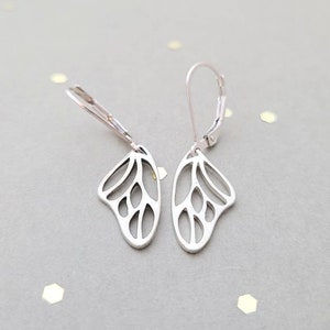 May include: A pair of silver butterfly earrings with a delicate, openwork design. The earrings have a leverback closure.