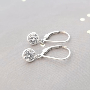 May include: A pair of silver dangle earrings with clear round cubic zirconia stones.