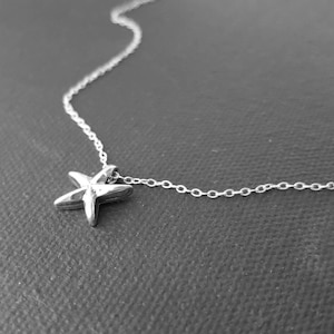 May include: A silver chain necklace with a small, silver starfish pendant.