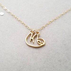 May include: A gold necklace with a delicate, cutout sloth charm. The chain is thin and delicate, and the sloth is hanging from a small loop.