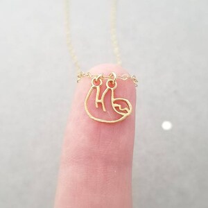 May include: A gold chain necklace with a small, delicate gold sloth pendant.