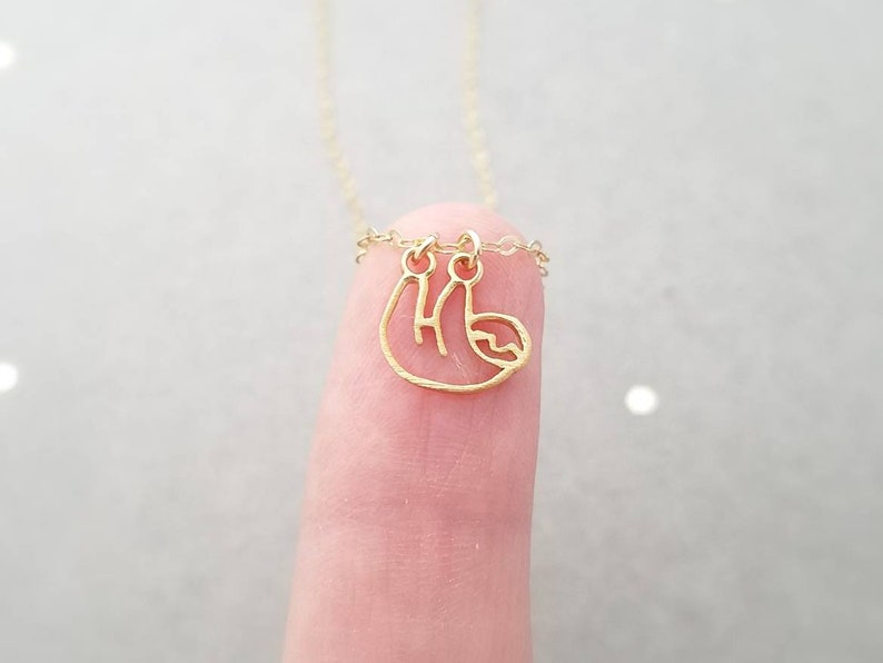 May include: A gold chain necklace with a small, delicate gold sloth pendant.