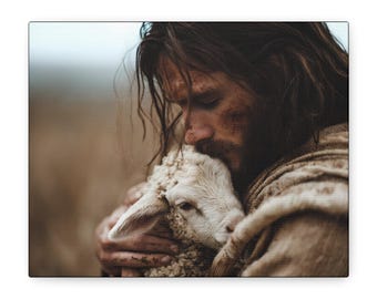 May include: A person with long brown hair and a beard, wearing a textured tan garment, holds a small white lamb close to their face. The person has smudges of dirt on their forehead and cheek, and the lamb has soft, curly white wool.