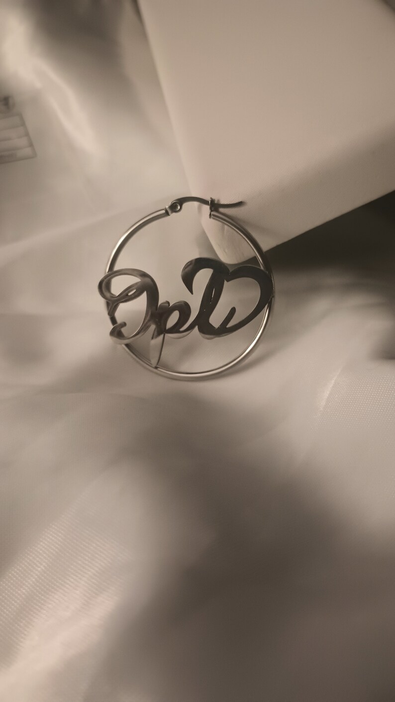 Puede incluir: Pendientes de aro de plata con el nombre "Opal" escrito en cursiva.