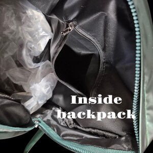 Peut inclure: L'int&eacute;rieur d'un sac &agrave; dos vert avec une fermeture &eacute;clair. Le sac &agrave; dos est ouvert et l'int&eacute;rieur est noir.