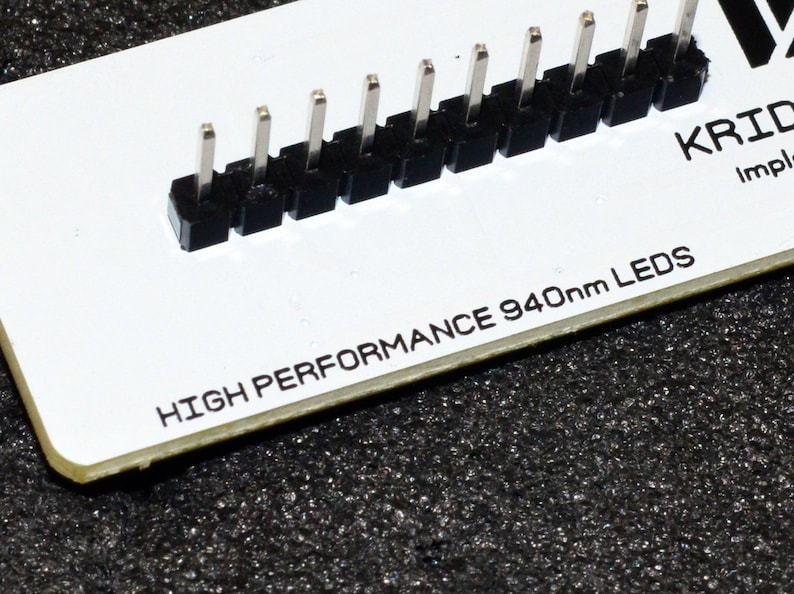 K&ouml;nnte beinhalten: Eine wei&szlig;e Leiterplatte mit einer Reihe schwarzer Stecker und silbernen Pins. Der Text "HIGH PERFORMANCE 940nm LEDs" ist auf der Platine aufgedruckt. Die Platine liegt auf einer dunklen, strukturierten Oberfl&auml;che.