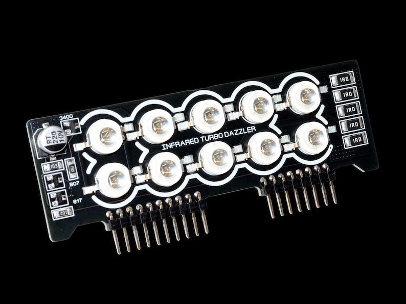 Może przedstawiać: Czarna płytka drukowana z napisem "INFRARED TURBO DAZZLER" i wieloma białymi diodami LED. Płytka posiada kilka pin&oacute;w i małe elementy elektroniczne. Tło jest jednolicie czarne.