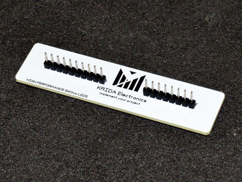 K&ouml;nnte beinhalten: Eine wei&szlig;e Leiterplatte mit schwarzen Stiftleisten. Auf der Platine steht der Text "HIGH PERFORMANCE 940nm LEDs" und "KRIDA Electronics implement your project". Die rechteckige Platine liegt auf einer dunklen, strukturierten Oberfl&auml;che.
