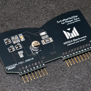 Puede incluir: Placa de circuito negra con pines dorados y componentes electr&oacute;nicos, etiquetada como "InfraRed DaZZier for Flipper Zero". La placa tiene el texto "KRIDA Electronics" y "rev1.0".