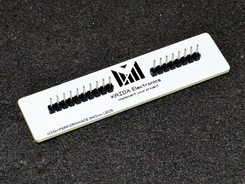 K&ouml;nnte beinhalten: Eine wei&szlig;e, rechteckige Leiterplatte mit schwarzen Steckern und silbernen Stiften. Die Platine tr&auml;gt den Text "KRIDA Electronics" und "Implement your project". Der Text "HIGH PERFORMANCE 940nm LEDs" ist ebenfalls sichtbar.