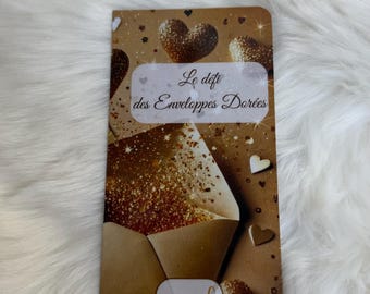 May include: A rectangular card featuring a gold envelope graphic with glitter accents, heart shapes, and the text Le défi des Enveloppes Dorées. A white oval space with a euro symbol is at the bottom. Above the card is a gold-colored hand sculpture.