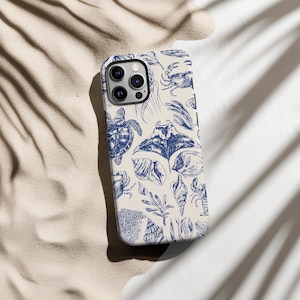 Könnte beinhalten: Eine weiße Handyhülle mit einem blauen und weißen Muster aus Meeresbewohnern, darunter eine Schildkröte, ein Rochen, ein Krebs und Muscheln.